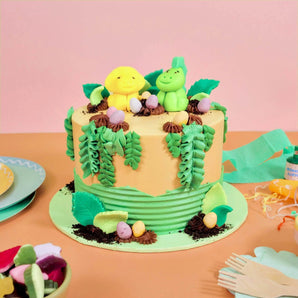 Dinosaur Cake with handmade fondant dinos, buttercream foliage, chocolate soil, and edible eggs by Crumbs & Doilies.